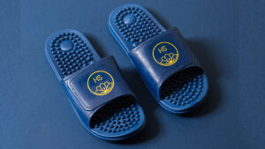 Pair of navy PVC massaging sliders with textured footbed on a navy background