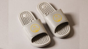 Pair of silver PVC massaging sliders with raised footbed texture on a light background