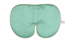 An oversized jade‑green silk sleep mask with smooth fabric, gold edging, and a soft curved shape.