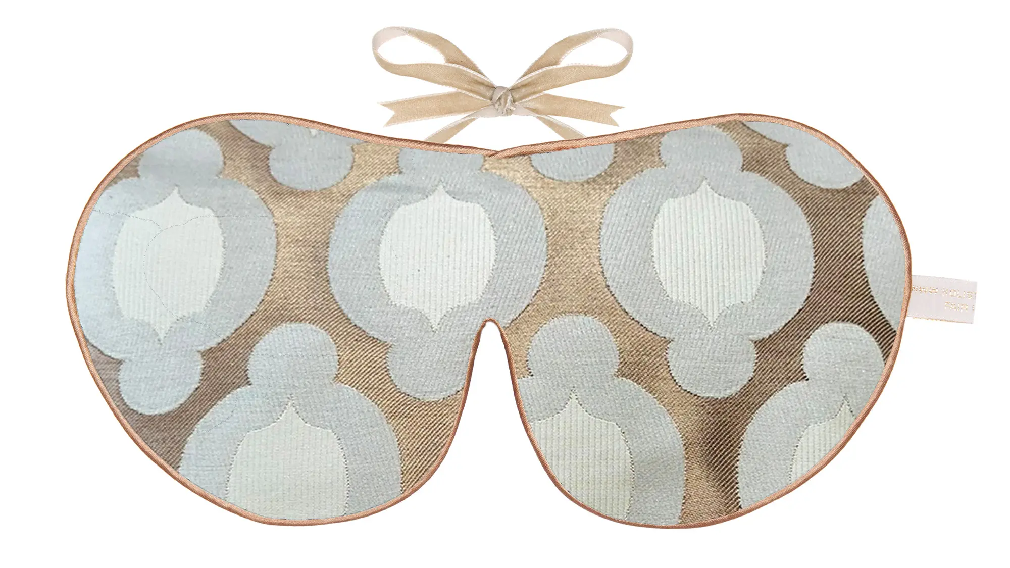 A silk sleep mask with a geometric woven pattern in soft blue and taupe tones, finished with gold edging and beige ribbon ties.