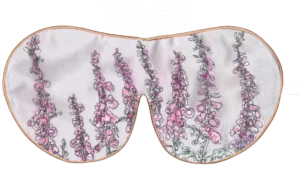 Silk sleep mask featuring a botanical foxglove print in pink and lilac tones on a soft neutral background.