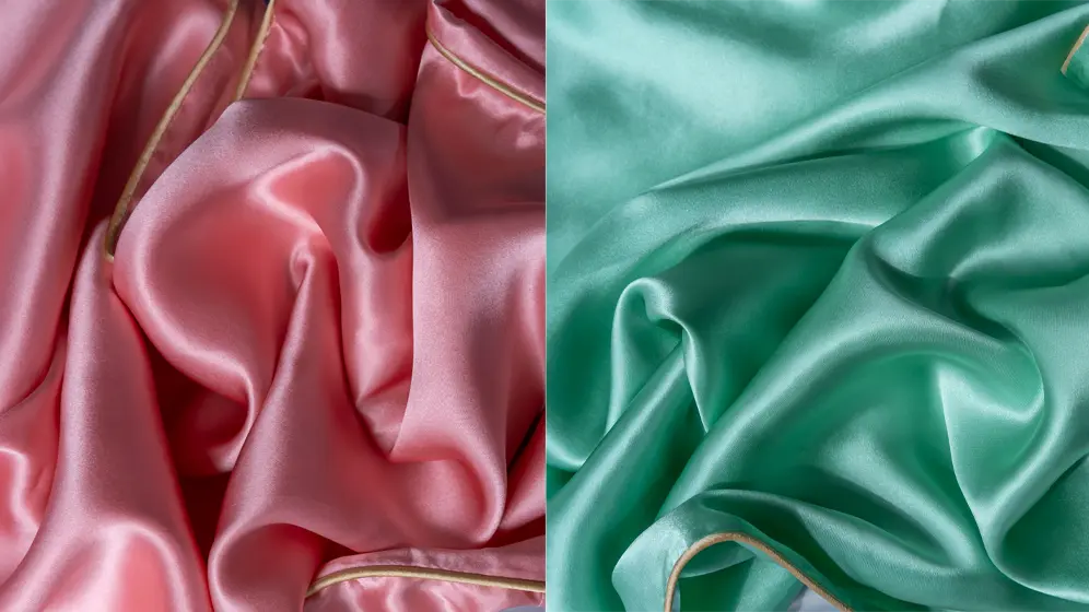 Close‑up of rose pink and jade green silk fabric with soft folds and a smooth, glossy texture.