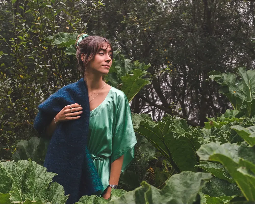 Person standing in lush greenery surrounded by tall, broad‑leaf plants.