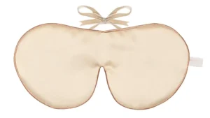 Cream silk sleep mask with a soft bow tie fastening.