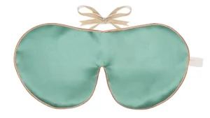 Jade silk sleep mask with honey‑coloured piping and silk ribbon tie, shown flat on a white background.