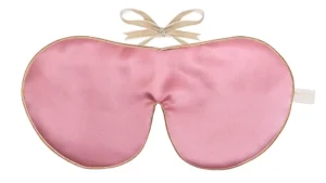 Rose colour silk sleep mask with honey‑coloured piping and silk ribbon tie, shown flat on a white background.